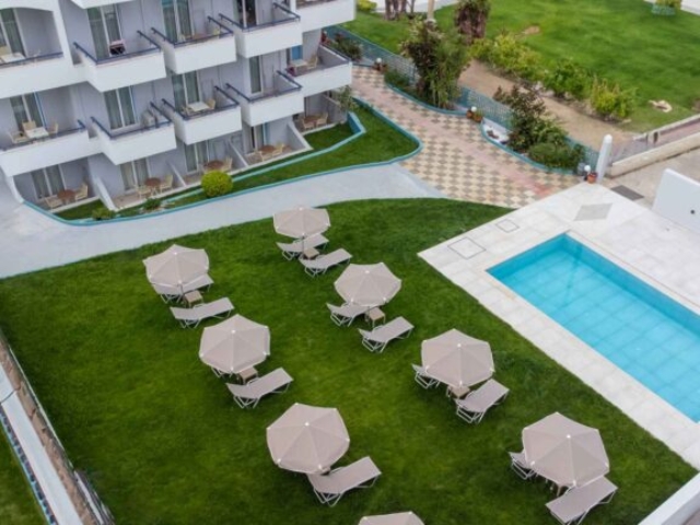 Bird's eye view of building & swimming pool with loungers & umbrellas