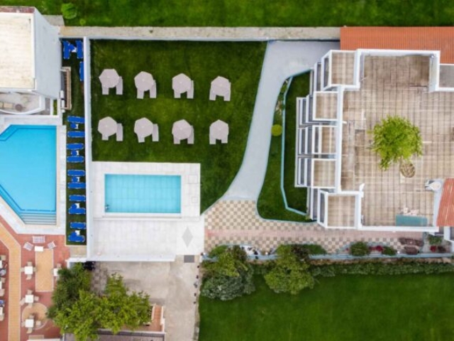 Bird's eye view of building & swimming pool with loungers & umbrellas